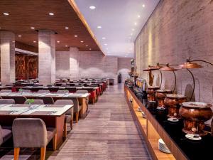 雅加达雅加达哈莫尼美爵酒店的用餐室配有长桌子和椅子