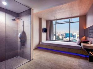 雅加达雅加达哈莫尼美爵酒店的一间带一张床和淋浴的浴室以及窗户