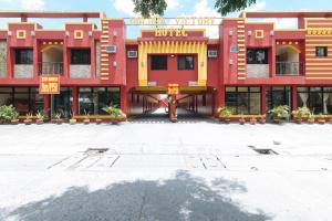 MabalacatRedDoorz @ Golden Victory Hotel Mabalacat Pampanga的一座红色和黄色的建筑,有很多窗户