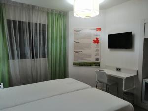 马德里马德里普拉多宜必思尚品酒店的一间卧室配有一张床、一张书桌和一台电视。