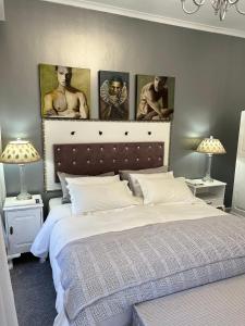 西萨默塞特Somerset West Garden Apartments 1的卧室配有一张墙上三幅画作的床