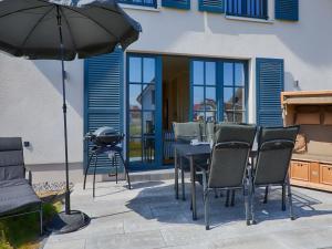 德兰斯克Reetland am Meer - Luxus Reetdachvilla mit 3 Schlafzimmern, Sauna und Kamin F15的庭院配有桌椅和遮阳伞。