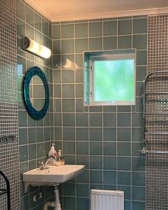 TivedGrönelid Gård的绿色瓷砖浴室设有水槽和窗户