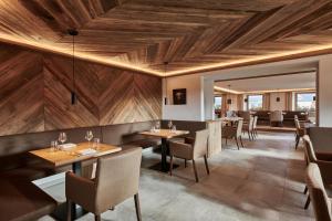 霍伊塞尔恩ADLER HÄUSERN Gourmet & Spa Hotel的餐厅设有木制天花板和桌椅