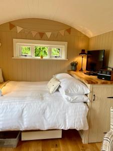 MountnugentSheelin Shepherds Hut 2 with Hot Tub的卧室配有白色的床和电视。