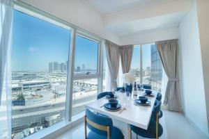 迪拜Blue dream apartment with Harbour view in Dubai Marina的一间带桌椅和大窗户的用餐室
