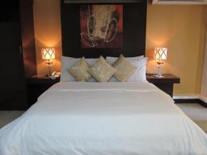 马尼拉牡蛎广场酒店 的一间卧室配有一张带两盏灯的大型白色床。