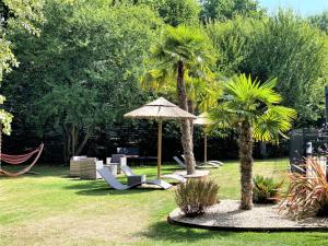 索米尔Hotel Restaurant Du Parc Saumur Logis Elégance的一个带椅子和遮阳伞的庭院,棕榈树