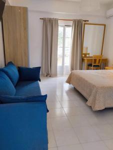 莱夫基米Alykes Family Resort的一间卧室配有一张床和一张蓝色的沙发