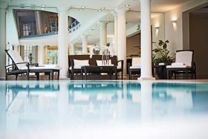 维也纳Palais Coburg Hotel的酒店大堂的游泳池,配有桌椅