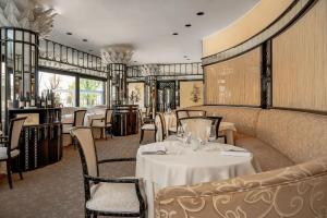 里米尼Hotel Imperiale Rimini & SPA的一间设有白色桌椅的用餐室