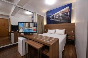 塔瓜汀加S4 Hotel Águas Claras的一间卧室配有一张床和一张带显示器的书桌
