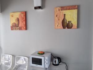 陶尔米纳Villa Glamour的一张配有微波炉的桌子和墙上的两张照片