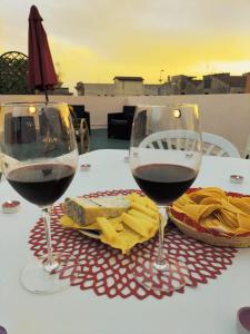卡利亚里Rosa's Apartment with Terrace的桌子上放两杯红葡萄酒和奶酪