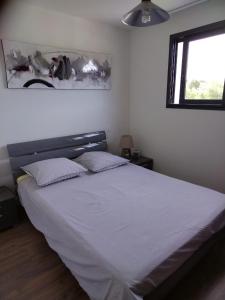 安格雷ANGLET petite Maison à 2 kms des plages et de Biarritz的卧室配有一张带白色床单的大床和窗户。