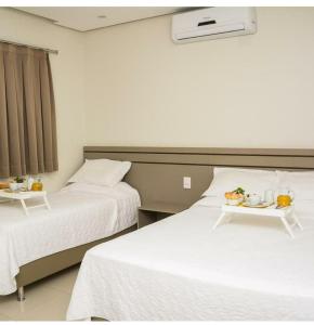 古鲁皮Hotel Imperador的酒店客房设有两张床和一盘食物
