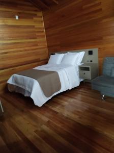 邦雅尔丁-达塞拉Cabanas Sol Poente的卧室配有一张白色大床和一把椅子