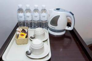 瑟纳旺D&F BOUTIQUE HOTEL SENAWANG的咖啡壶和装有水瓶的托盘上的杯子