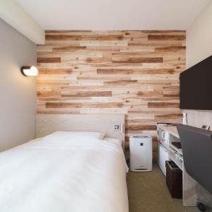 东京东京蒲田JR西口超级酒店的一间卧室设有一张床和木墙