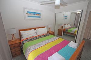 科夫斯港Paradise Waters 13的一间卧室配有一张色彩缤纷的床和镜子