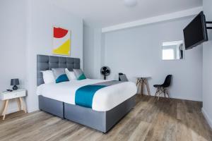 大雅茅斯OYO Studiotel GY - Modern Hotel Apartments的一间卧室配有一张床和一台平面电视