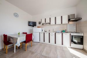 班约勒Apartments Mladenka in Banjol的厨房配有白色橱柜和红色椅子的桌子