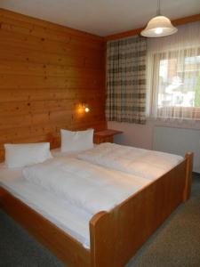 施图拜河谷新施蒂夫特Pension Holzknechthof am See的卧室内的一张大床,设有木墙