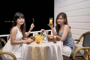 巴淡岛中心Morelo Water Villa的两个坐在桌子边喝着饮料的女人