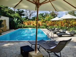恩纳Homm Stay Yumiha Okinawa by Banyan Tree Group的一个带椅子和遮阳伞的游泳池
