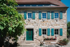 ArnsdorfIdyllischer Bauernhof mit viel Charme的一座带蓝色百叶窗和绿色门的石头房子