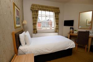 斯塔福德Vine, Stafford by The White Feather Group Ltd的配有一张床、一张书桌和一扇窗户的酒店客房