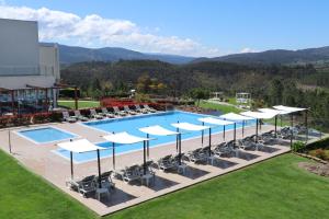 蒙丁-迪巴什图Agua Hotels Mondim de Basto的一个带白色遮阳伞和椅子的室外游泳池