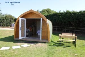 HappisburghLanterns Shepherds Huts & Glamping的草上的小木帐篷,带长凳