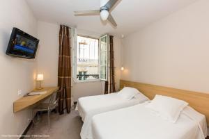 波尔多Hotel Gambetta的酒店客房设有两张床、一张桌子和一台电视。