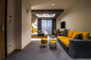 萨帕雷瓦巴尼亚EMAR HOTEL & SPA的一间带黄色沙发的客厅和一间卧室