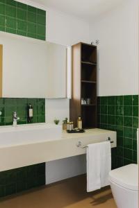 蓬塔德尔加达蓬塔德尔加达酒店的浴室设有水槽、卫生间和绿色瓷砖。