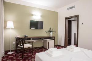 克拉约瓦Hotel Relax Craiova的酒店客房设有一张桌子和一台墙上的电视
