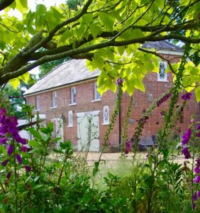 福丁布里奇The Georgian Coach House:New Forest with hot tub的一座古老的砖砌建筑,前面有鲜花