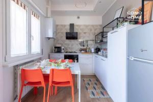 科莫Como Holiday Home Appartamento ideale per famiglie的厨房配有桌椅和冰箱。