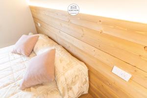 蓬泰迪莱尼奥B&B Alpen Suite Ponte di Legno的一张带两个枕头的床和木墙