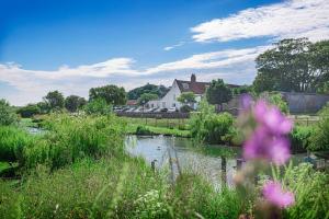 布莱克尼The Manor Coastal Hotel & Inn, Blakeney, Norfolk的河水田里,有房子的背景