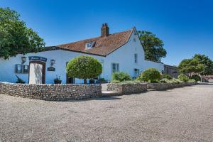 布莱克尼The Manor Coastal Hotel & Inn, Blakeney, Norfolk的前面有石墙的白色房子