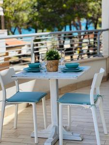 锡尔维玛丽娜Beach apartments Spiaggia Nascosta的一张带两把椅子的白色桌子和盆栽植物