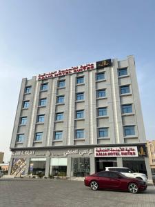 索哈尔Aalia Hotel Suites的停在大楼前的红色汽车