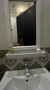 布赖代Reef Al Qassim Hotel Apartments的浴室水槽和镜子上方的电视
