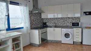 奥尔索拉APARTAMENTO ROQUE DEL ESTE的厨房配有白色橱柜、洗衣机和烘干机