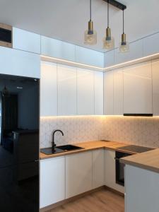 厄尔科Ełk Vacation Apartament的厨房配有白色橱柜和水槽