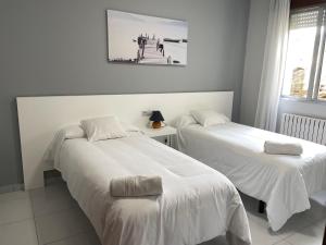 桑亨霍委内瑞拉酒店的客房内的两张床和白色床单