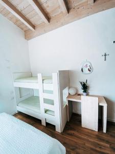 卡尔多纳佐AGRITURISMO DAL PEROTIN的卧室配有白色双层床和书桌