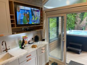 贝塞斯达P74 - Riverside Family Pod with Hot Tub的带浴缸的厨房以及大篷车内的电视